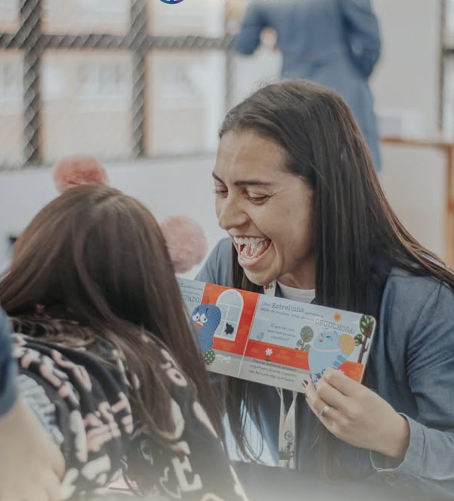 Terapeuta sorrindo enquanto lê um livro infantil com uma criança